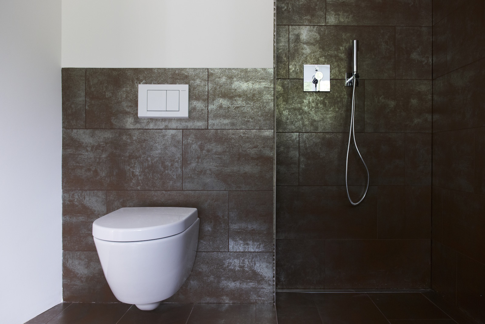 WC und Dusche mit dunklen grossflächigen Fliesen